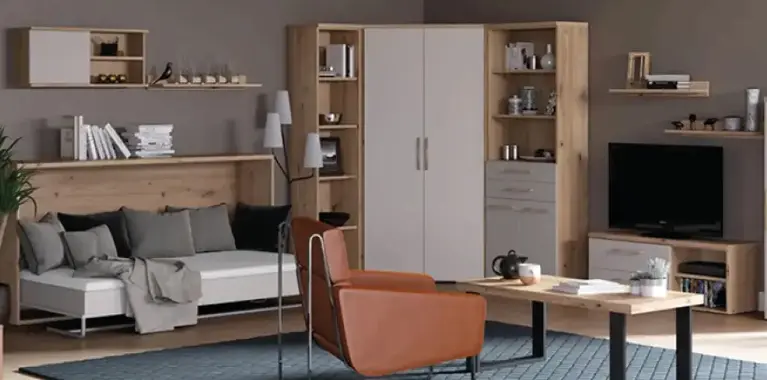 Komplette Wohnwand in Holz und Weiss mit Sofa, Eckschrank, Hängeregalen und TV-Board, vorn Couchtisch und cognacfarbenem Sessel auf blauem Teppich.